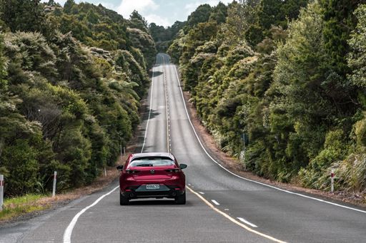 Auckland / New Zealand - January 10 2020: View of car driving on straight hilly road through Waitakere Ranges forest towards Piha village
