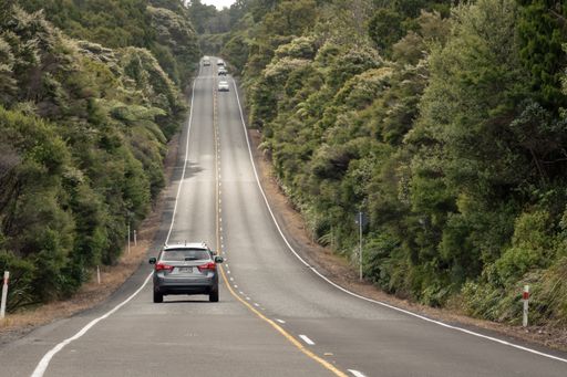 Auckland / New Zealand - January 10 2020: View of car driving on straight hilly road through Waitakere Ranges forest towards Piha village