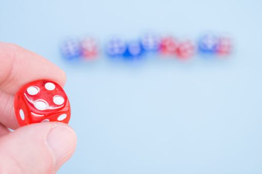 A closeup shot of a hand holding red dice isolated on light blue background