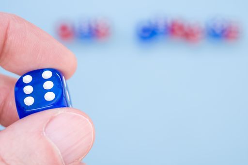 A closeup shot of a hand holding blue dice isolated on light blue background