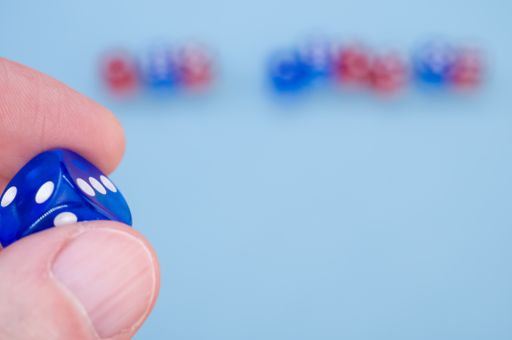 A closeup shot of a hand holding blue dice isolated on light blue background