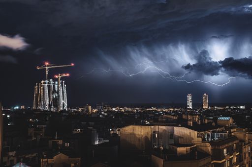 Lightnings brightening over the city of Barcelona pointing directly to the Sagrada Familia monument. You can see the clouds and the storm.