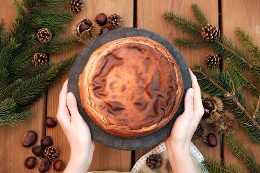 A top view of female hands serving a chestnut cheesecake over a wooden table