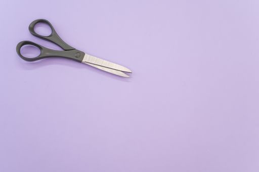 A top view of black scissors isolated on light violet background