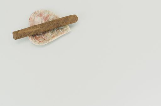 A top view of cigar on a heart-shaped tray with copy space isolated on white background