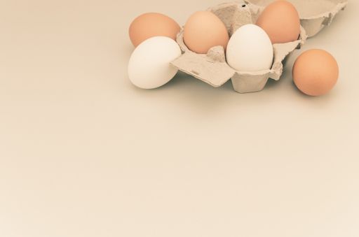 A high angle shot of organic fresh eggs on a tray isolated on light brown background