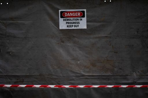 A closeup shot of a danger sign that has the message Demolition in Progress