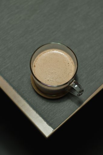 A vertical shot of a cappuccino in a transparent mug