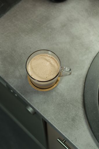 A vertical shot of a cappuccino in a transparent mug
