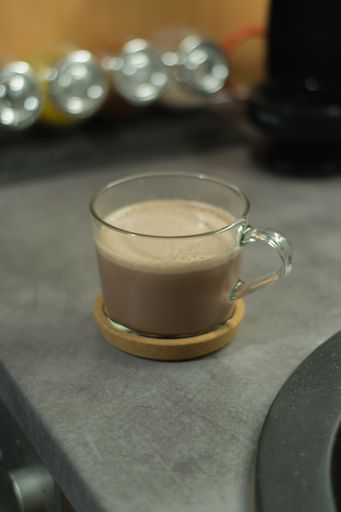 A vertical shot of a cappuccino in a transparent mug