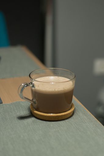 A vertical shot of a cappuccino in a transparent mug