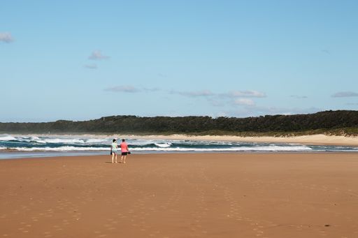 Two people walking on Sardinia bay beach. This is a popular tourist attraction in the city.