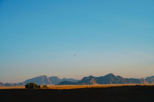A sunny Wadi Rum desert in Jordan, with the rocky formation in the background, with a fence of the Reserve