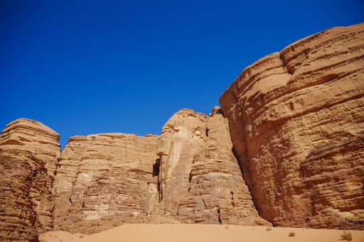 A scenic view of the ancient sandstone mountains of the Wadi Rum desert with a blue sky in the background