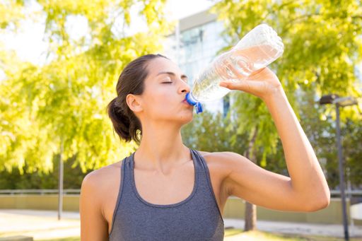 An athlete woman drinking cold water after jogging in the morning