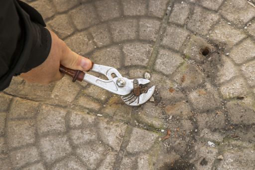 A high angle shot of a male holding an old bolt with an adjustable wrench