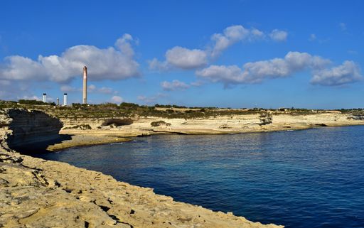 Wave-cut platform and low white limestone cliffs found along a St Peter's Pool bay in Malta, on a sunny winter day with calm blue sea in Delimara Malt