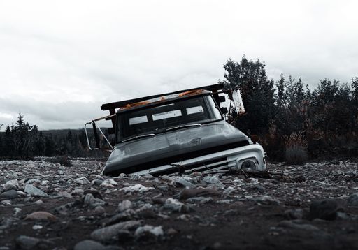 A grayscale shot of an old rusty abandoned truck, buried in river bed in Denali national park, Alaska