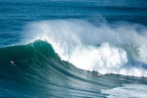 The big foamy waves of the Atlantic Ocean near the Nazare municipality in Portugal and surfers riding