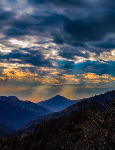 A beautiful vertical view of mountains during sunset under the cloudy sky