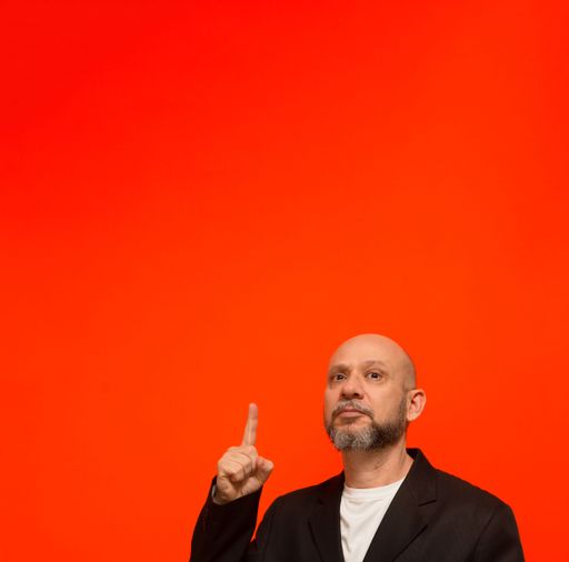 Business man, mature, elegant, pointing his finger up. Isolated on orange background.