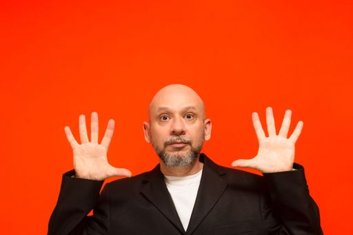 Portrait of a stylish business man making hand gestures. Looking at the camera. Isolated on orange background.