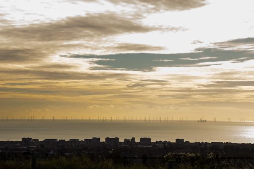 The beautiful sea and cloudy sky at sunset with wind turbines in the background. Brighton, UK.