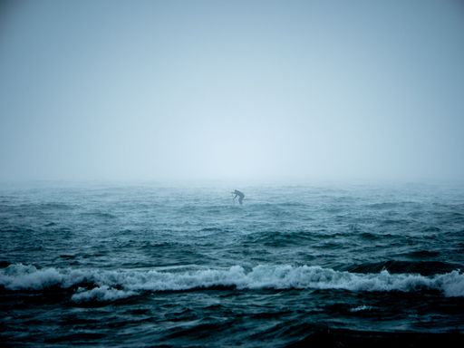 A man paddling on a rough sea during foggy day