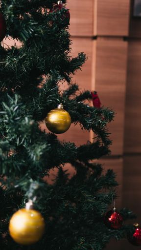 A vertical closeup shot of decorating a Christmas tree