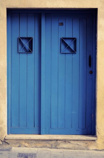 A beautiful shot of a blue wooden door of a white stone building during daytime