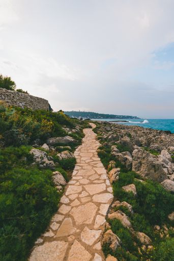 A vertical shot of a beautiful cobblestone road at the shore of the ocean on a gloomy day