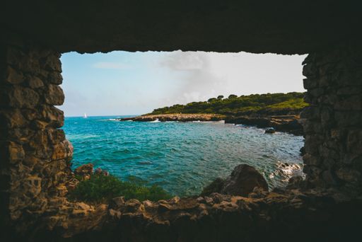 The beautiful turquoise water of the sea captured from the inside of a cave with a square window