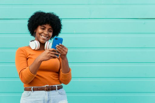 A closeup shot of a young attractive lady wearing headphones using her phone