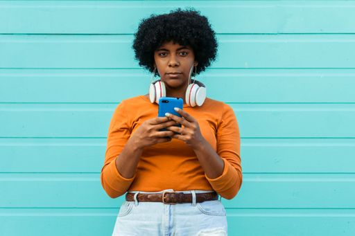 A closeup shot of a young attractive lady wearing headphones using her phone