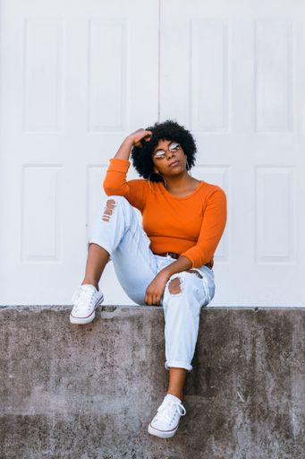 A vertical shot of a young attractive lady wearing jeans, a long-sleeve t-shirt, sneakers