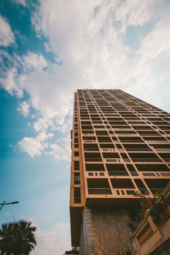 A vertical low angle shot of a high building under the cloudy sky