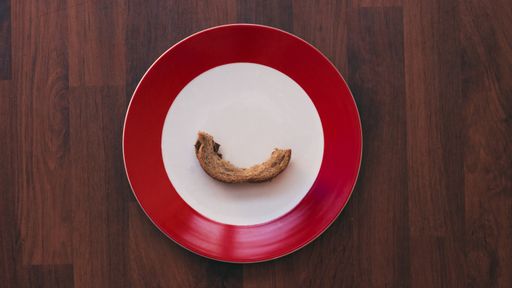 A top view of a half-eaten bread crust on a plate on a wooden table