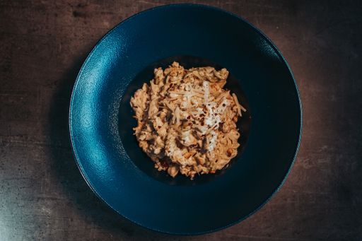 A top view of a bowl of cooked fusilli pasta with grated and melted cheese on the table