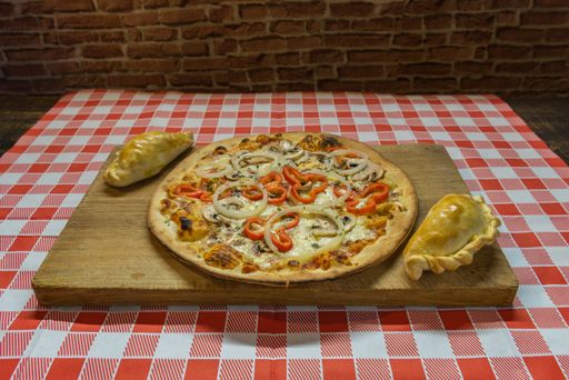 A closeup shot of pizza with cheese, red pepper, onions, and mushrooms on a wooden board
