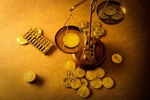A high angle shot of a bitcoin and coins on scales on the table - concept of futurism and banking