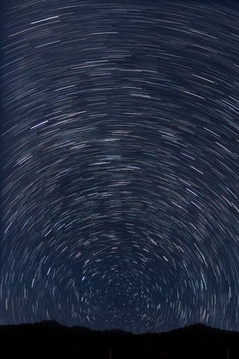 A silhouette shot of a mountain landscape on a swirling stars background