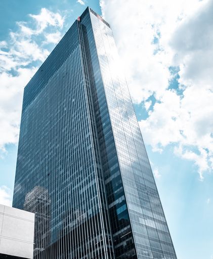 A vertical low angle shot of a modern glass business building touching the sky