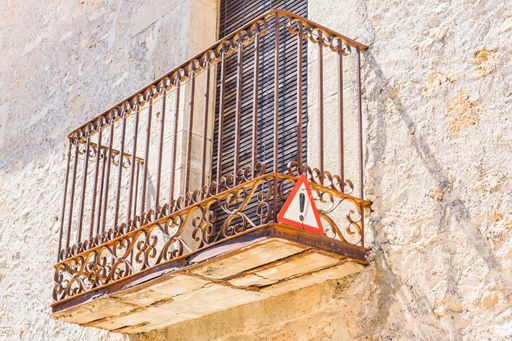 A low-angle shot of an old balcony with a warning sign on the side in Calatanazor, Spain