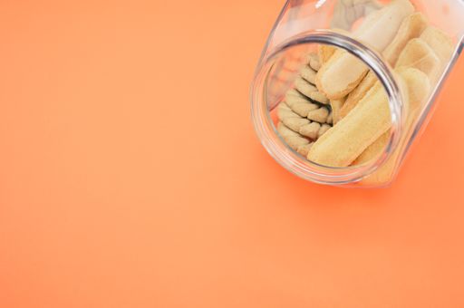 A high angle shot of a bowl of cookies on an orange surface