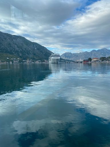 A vertical of a ship moored at the Bay of Kotor (Boka) against mountains in Montenegro on a cloudy day