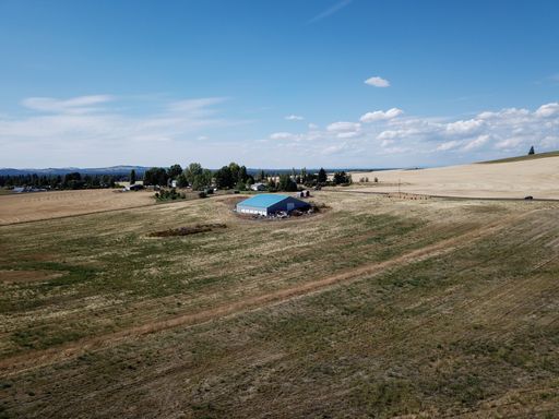 A high angle shot of a warehouse in the middle of a field under a blue sky at daytime
