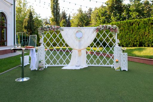 A vertical shot of a decorated wedding curtain hanging on a white fence in the park