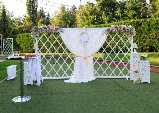 A vertical shot of a decorated wedding curtain hanging on a white fence in the park