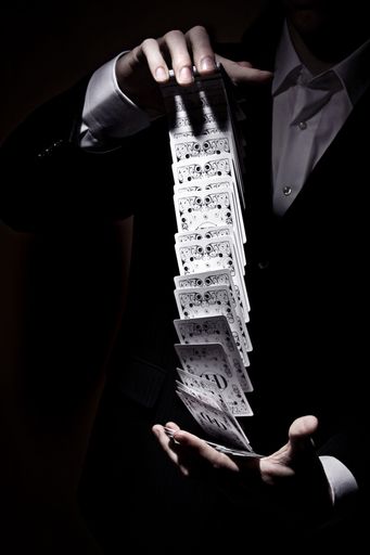 A vertical shot of a magician shuffling the cards in a cool way under the spotlight