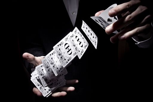A magician shuffling the cards in a cool way under the spotlight